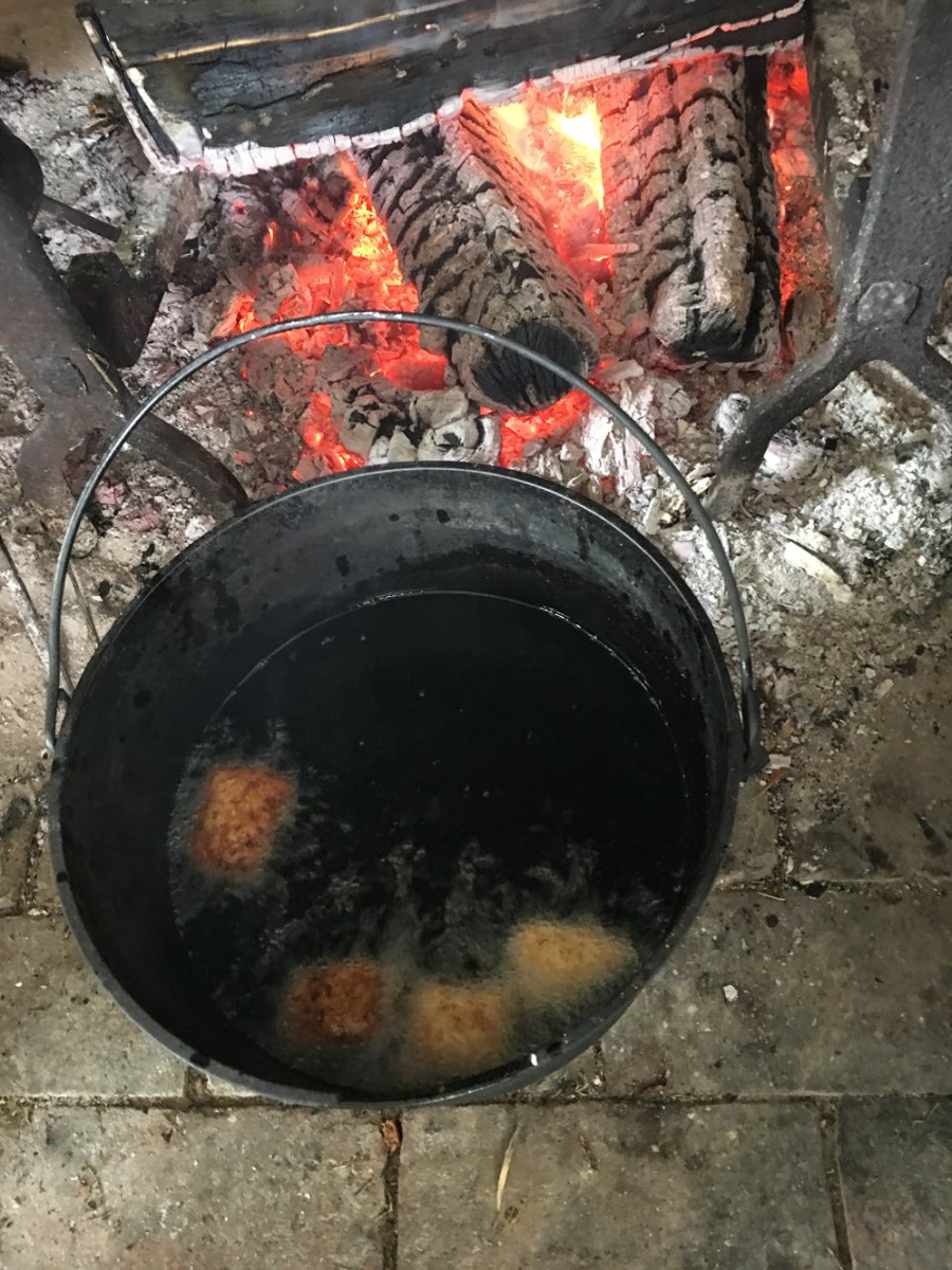 Doughnuts frying in kettle of lard